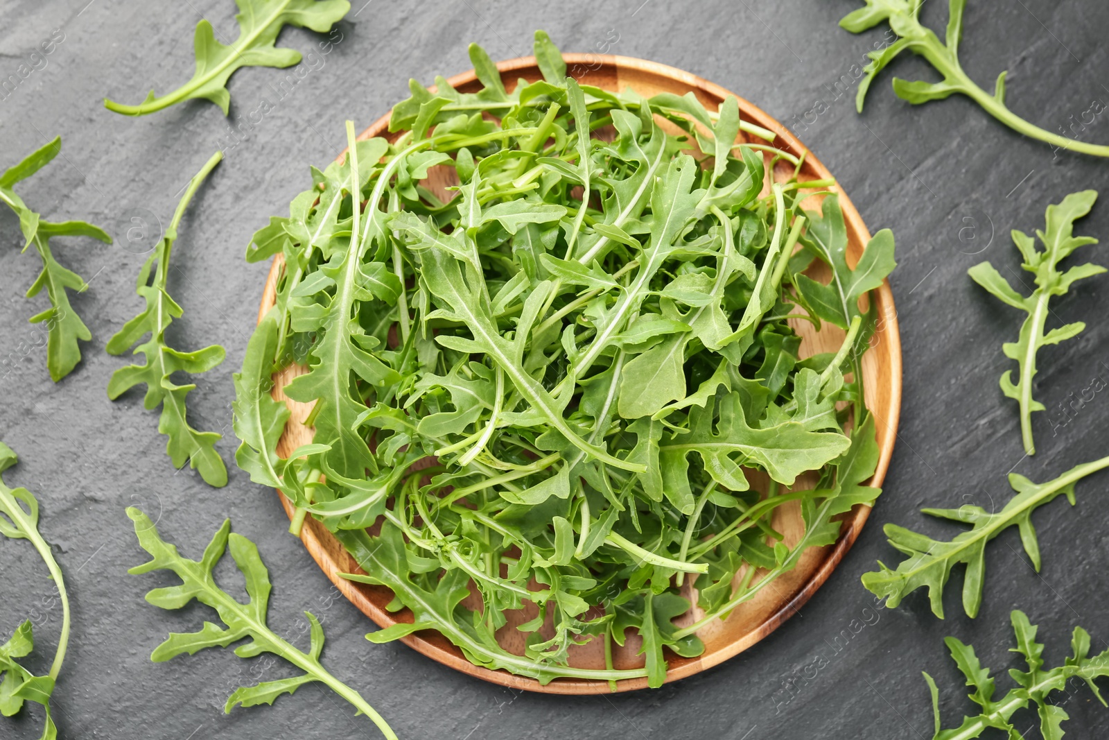 Fresh ripe green arugula leaves on black table, flat lay Photo of Fresh ripe green arugula leaves on black table, flat lay