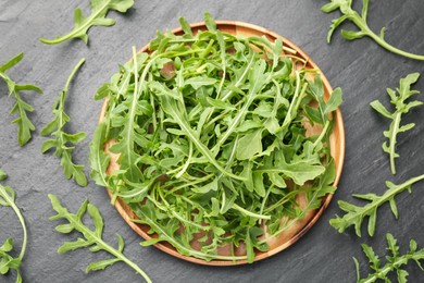 Photo of Fresh ripe green arugula leaves on black table, flat lay