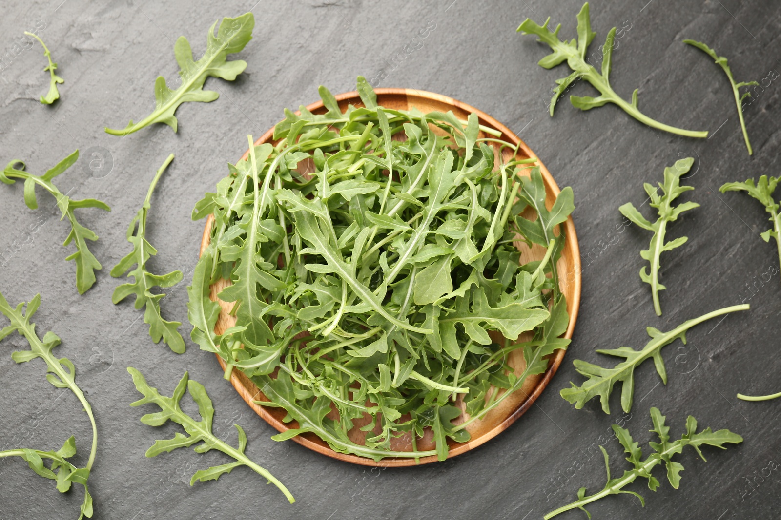 Fresh ripe green arugula leaves on black table, flat lay Photo of Fresh ripe green arugula leaves on black table, flat lay
