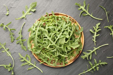 Photo of Fresh ripe green arugula leaves on black table, flat lay
