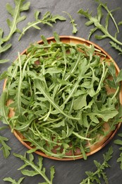 Photo of Fresh ripe green arugula leaves on black table, flat lay