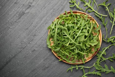 Photo of Fresh ripe green arugula leaves on black table, flat lay. Space for text