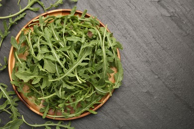 Photo of Fresh ripe green arugula leaves on black table, flat lay. Space for text