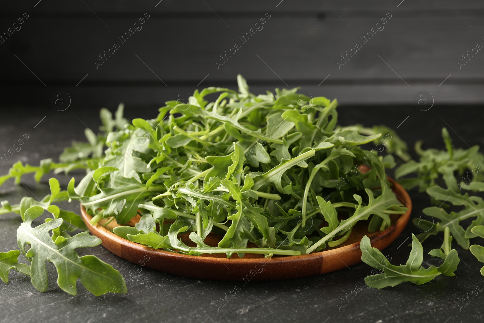 Fresh ripe green arugula leaves on black table, closeup Photo of Fresh ripe green arugula leaves on black table, closeup
