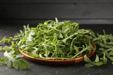 Photo of Fresh ripe green arugula leaves on black table, closeup