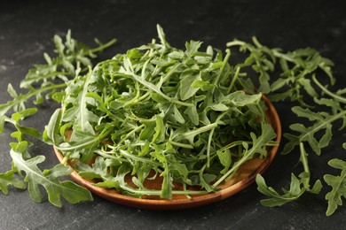 Photo of Fresh ripe green arugula leaves on black table, closeup