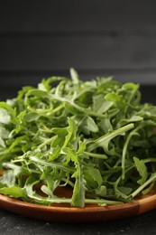 Photo of Fresh ripe green arugula leaves on black table, closeup