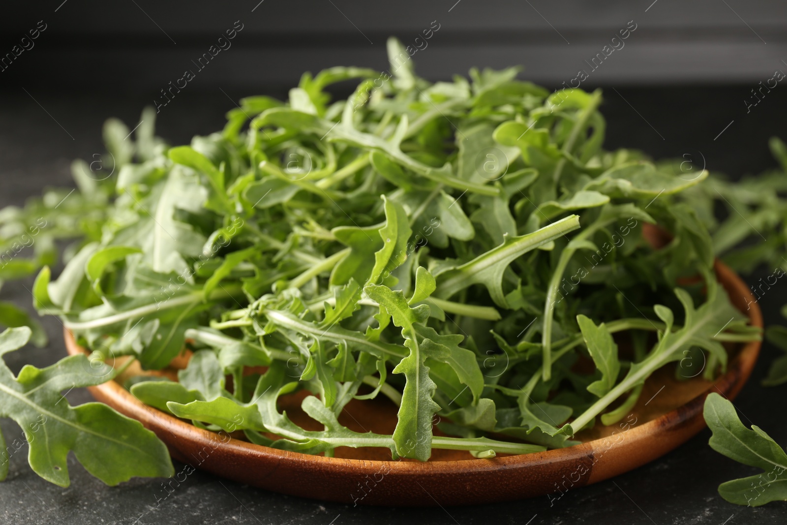 Fresh ripe green arugula leaves on black table, closeup Photo of Fresh ripe green arugula leaves on black table, closeup