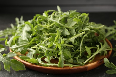 Photo of Fresh ripe green arugula leaves on black table, closeup