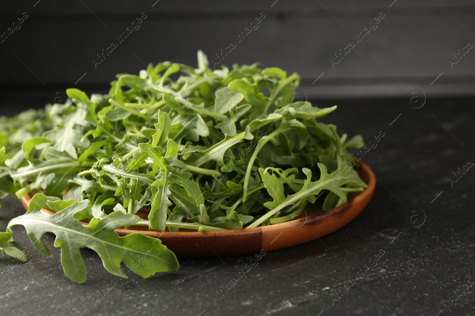 Fresh ripe green arugula leaves on black table, closeup Photo of Fresh ripe green arugula leaves on black table, closeup