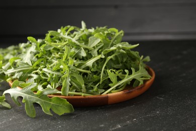 Photo of Fresh ripe green arugula leaves on black table, closeup