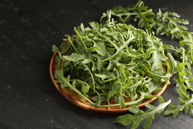 Photo of Fresh ripe green arugula leaves on black table, closeup