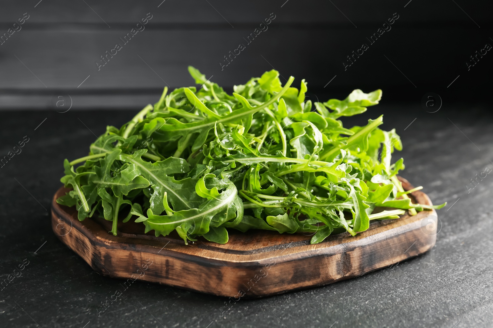Photo of Fresh ripe green arugula leaves on black table, closeup