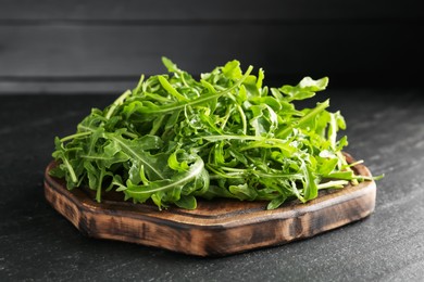 Photo of Fresh ripe green arugula leaves on black table, closeup