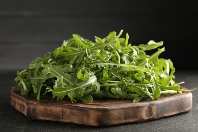 Photo of Fresh ripe green arugula leaves on black table, closeup