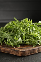 Photo of Fresh ripe green arugula leaves on black table, closeup