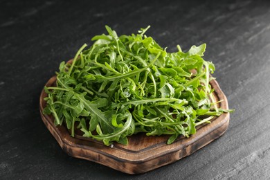 Photo of Fresh ripe green arugula leaves on black table, closeup