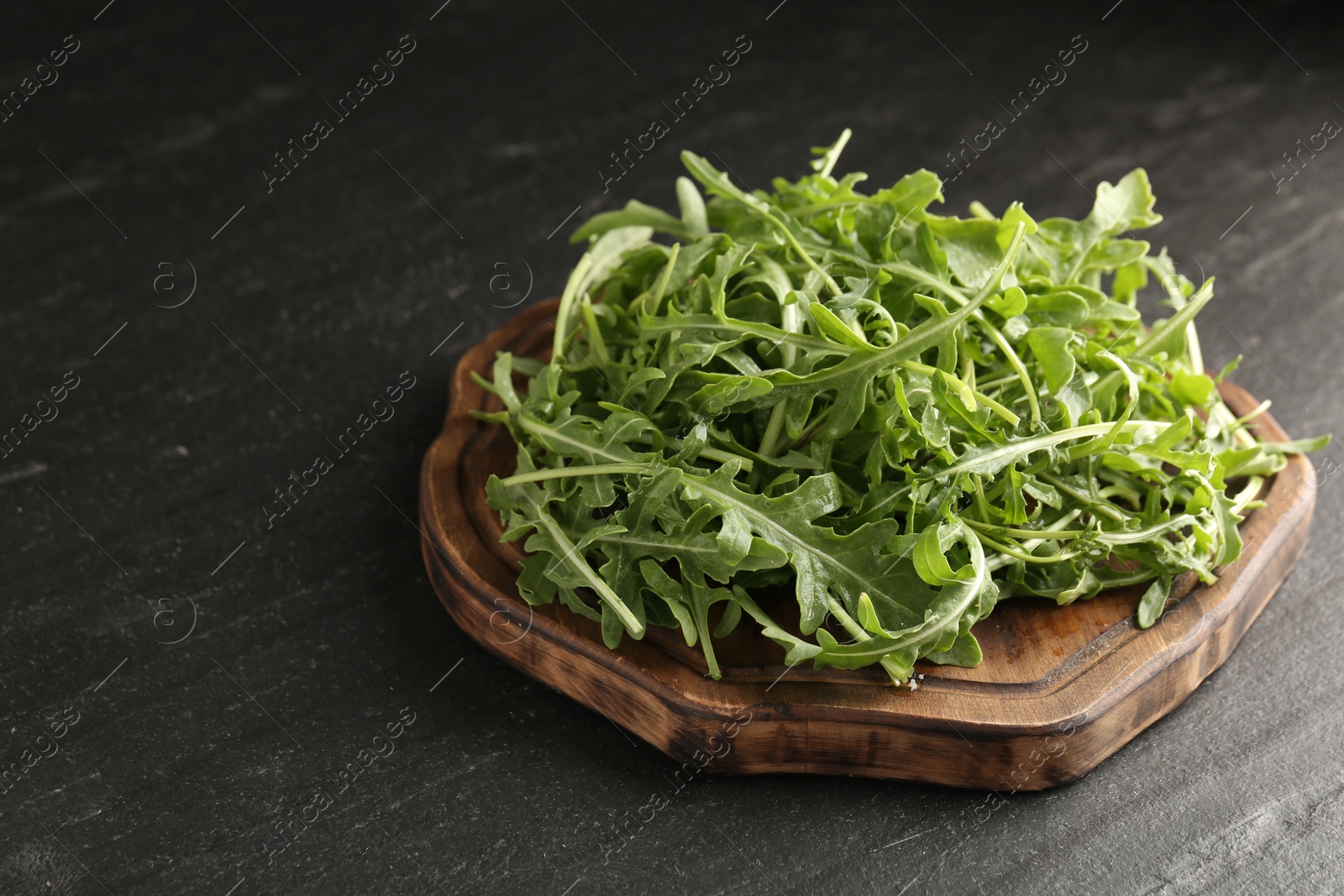 Fresh ripe green arugula leaves on black table, closeup. Space for text Photo of Fresh ripe green arugula leaves on black table, closeup. Space for text