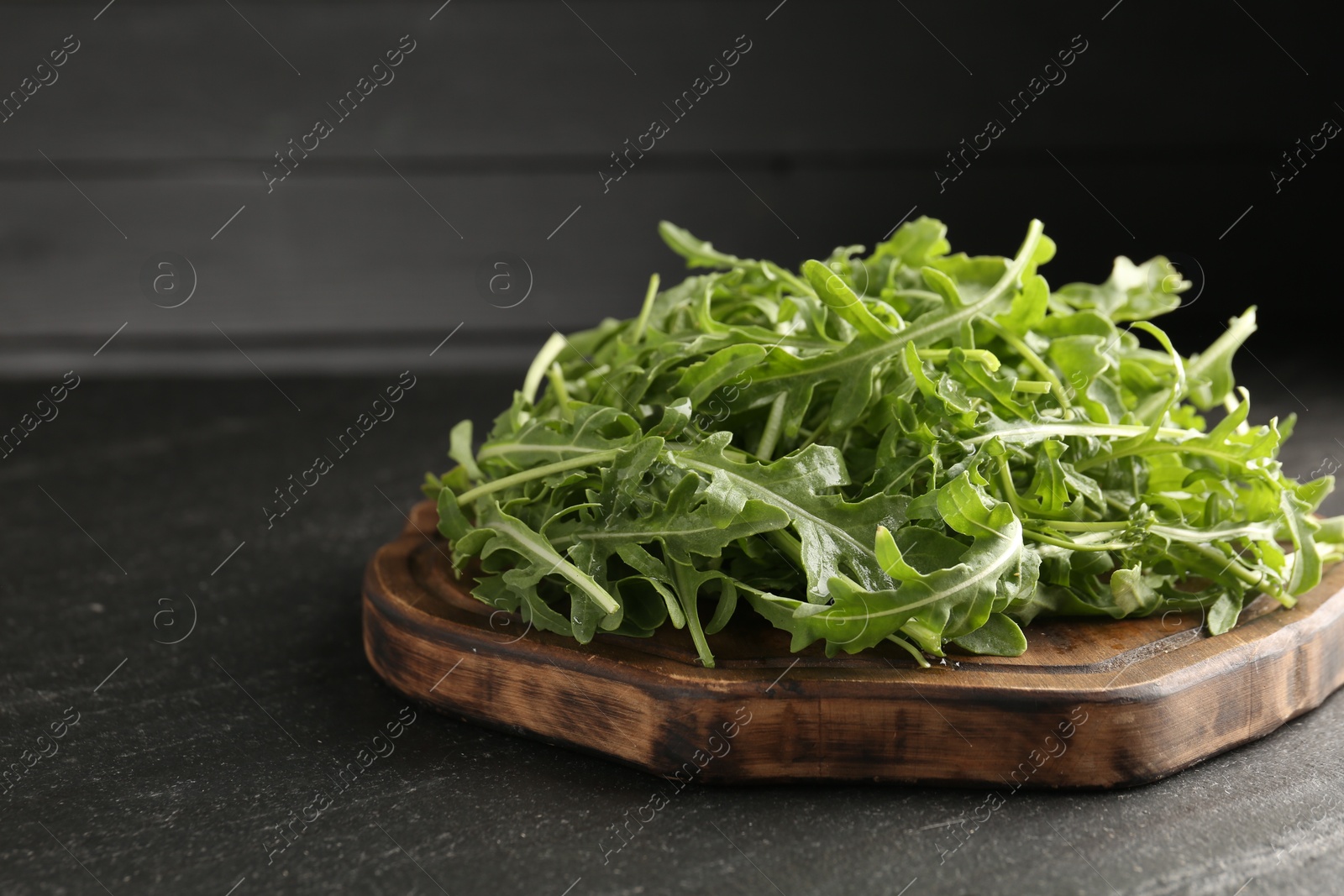 Fresh ripe green arugula leaves on black table, closeup. Space for text Photo of Fresh ripe green arugula leaves on black table, closeup. Space for text