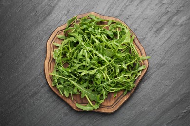 Photo of Fresh ripe green arugula leaves on black table, top view