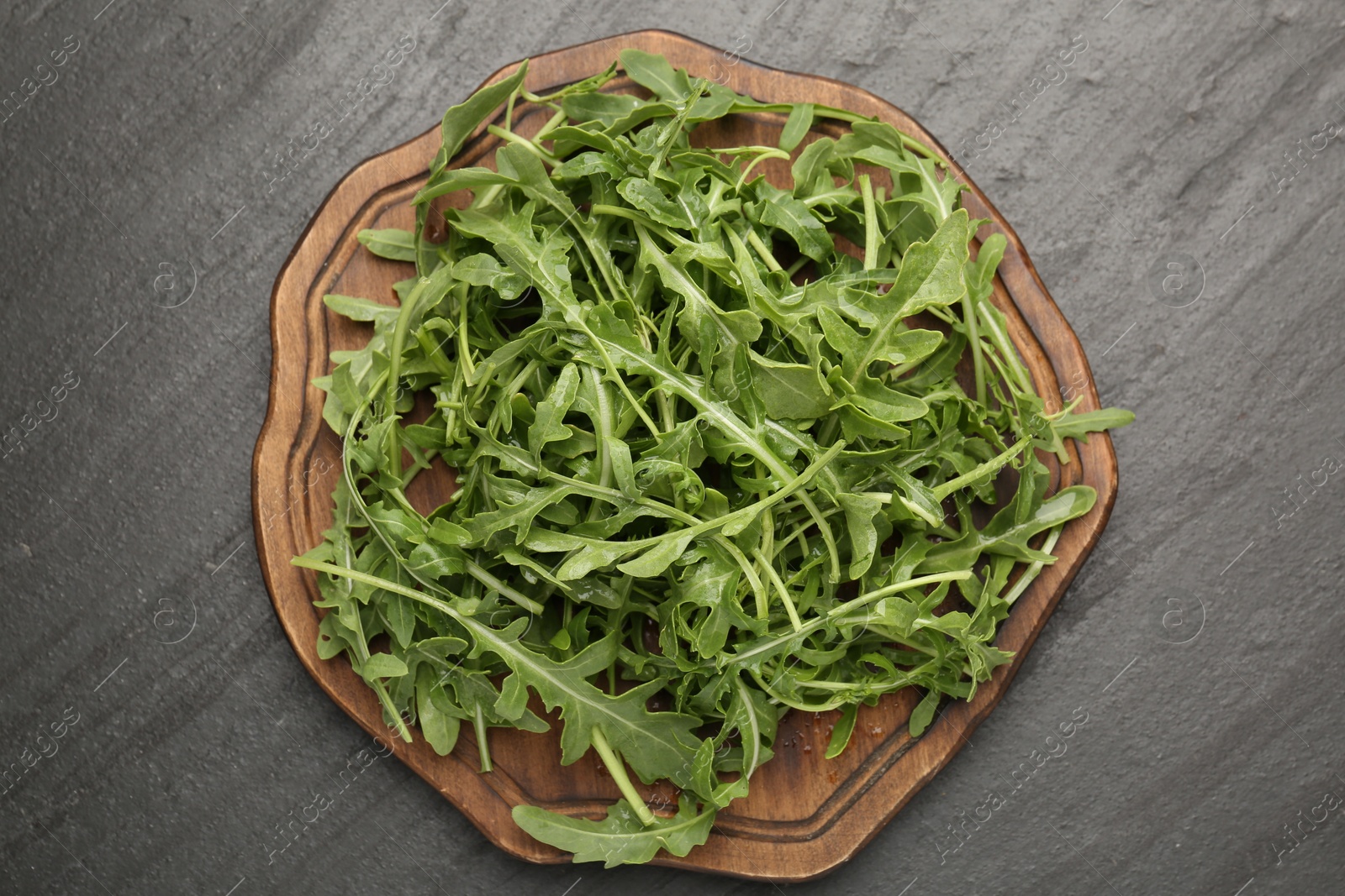 Fresh ripe green arugula leaves on black table, top view Photo of Fresh ripe green arugula leaves on black table, top view