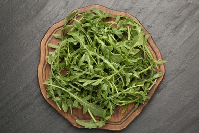 Photo of Fresh ripe green arugula leaves on black table, top view