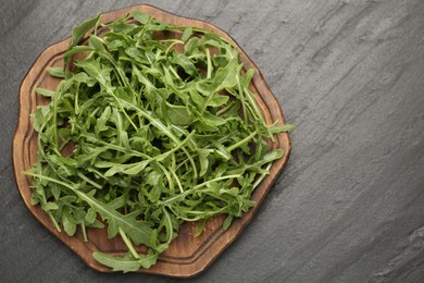 Photo of Fresh ripe green arugula leaves on black table, top view. Space for text