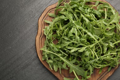 Photo of Fresh ripe green arugula leaves on black table, top view. Space for text