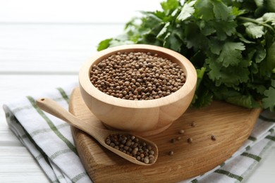 Photo of Coriander seeds and fresh cilantro on white wooden table, closeup