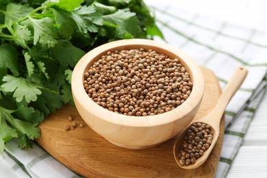 Photo of Coriander seeds and fresh cilantro on white wooden table, closeup