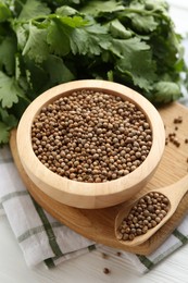 Photo of Coriander seeds and fresh cilantro on white wooden table, closeup