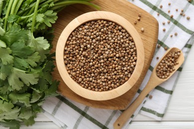 Photo of Coriander seeds and fresh cilantro on white wooden table, flat lay