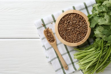 Photo of Coriander seeds and fresh cilantro on white wooden table, top view. Space for text