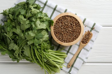 Photo of Coriander seeds and fresh cilantro on white wooden table, top view