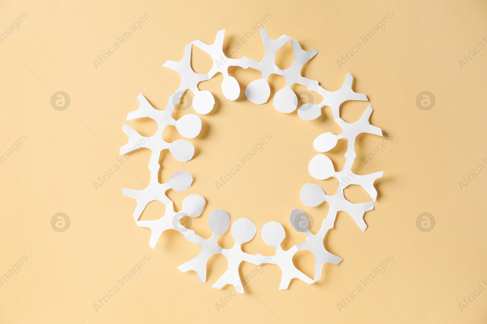 Paper figures of people holding hands on beige background, top view Photo of Paper figures of people holding hands on beige background, top view