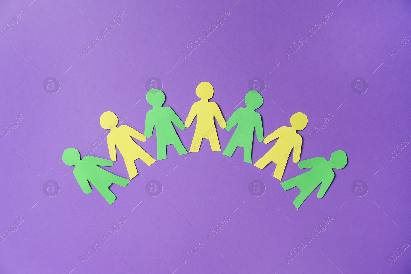 Photo of Paper figures of people holding hands on purple background, top view