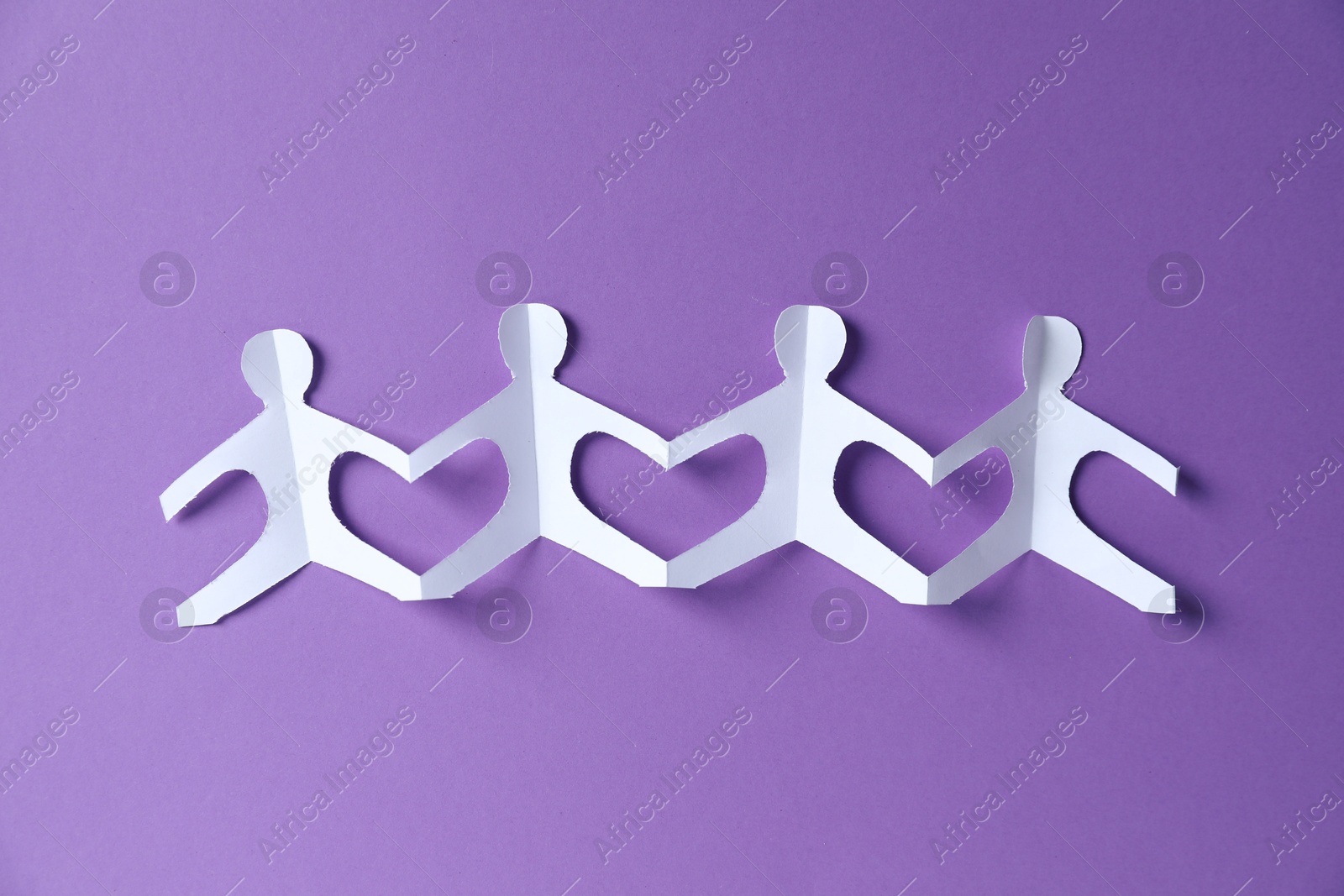 Paper figures of people holding hands on purple background, top view Photo of Paper figures of people holding hands on purple background, top view