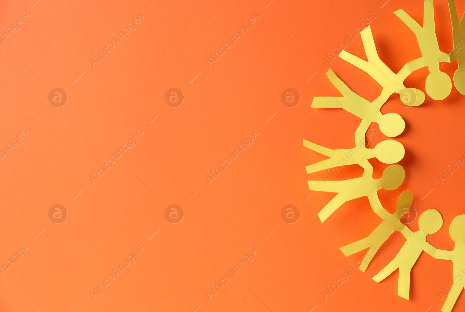 Photo of Paper figures of people holding hands on orange background, top view. Space for text