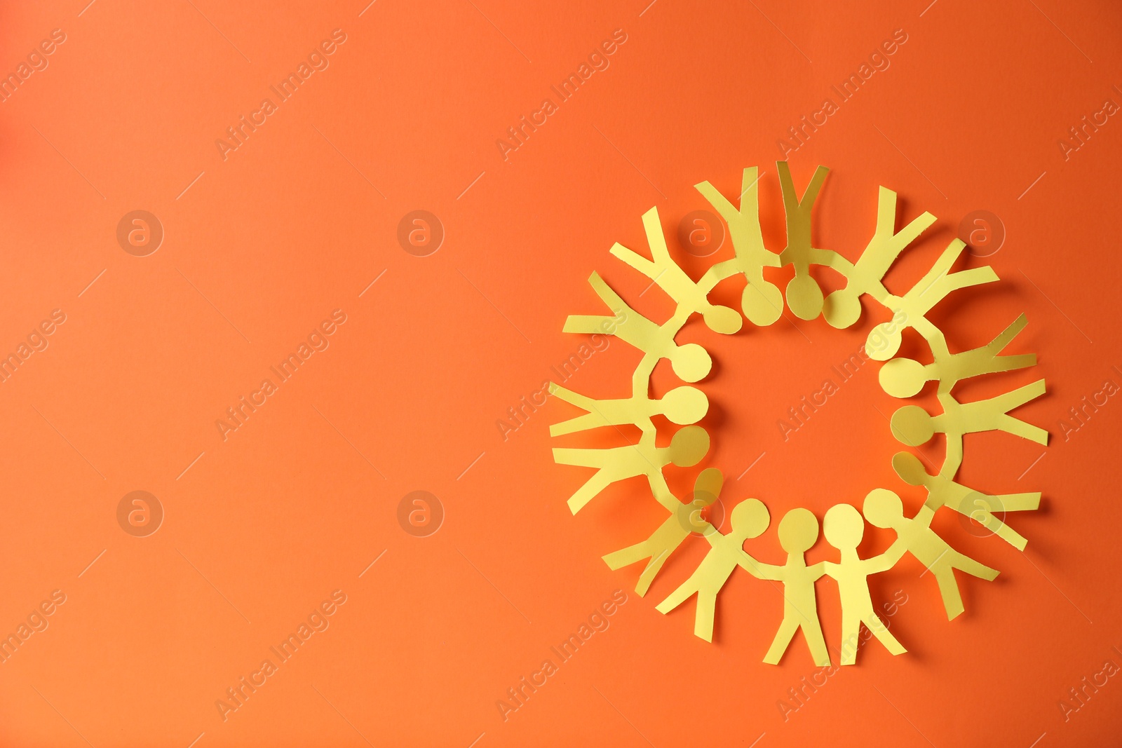 Photo of Paper figures of people holding hands on orange background, top view. Space for text