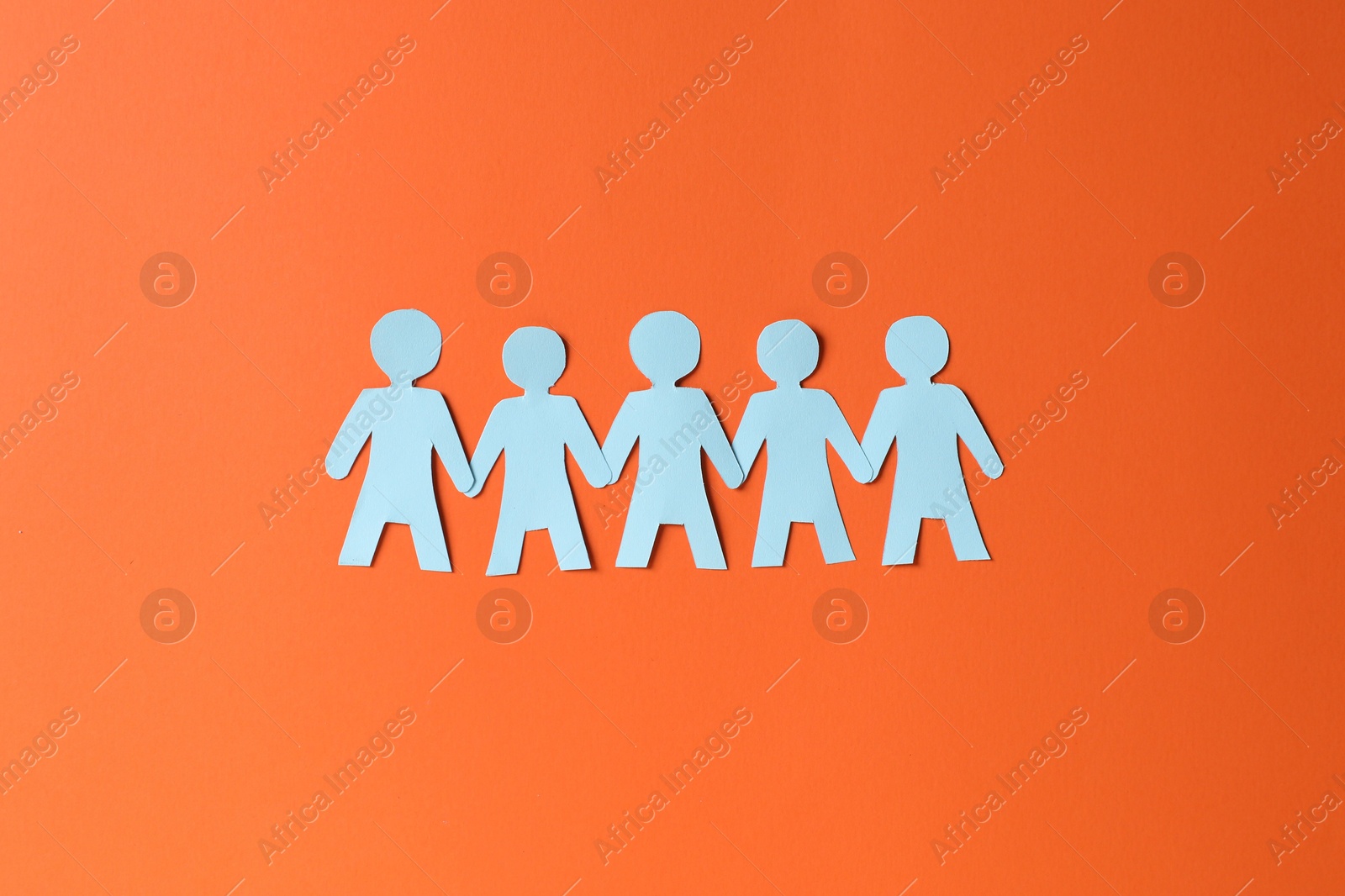 Paper figures of people holding hands on orange background, top view Photo of Paper figures of people holding hands on orange background, top view