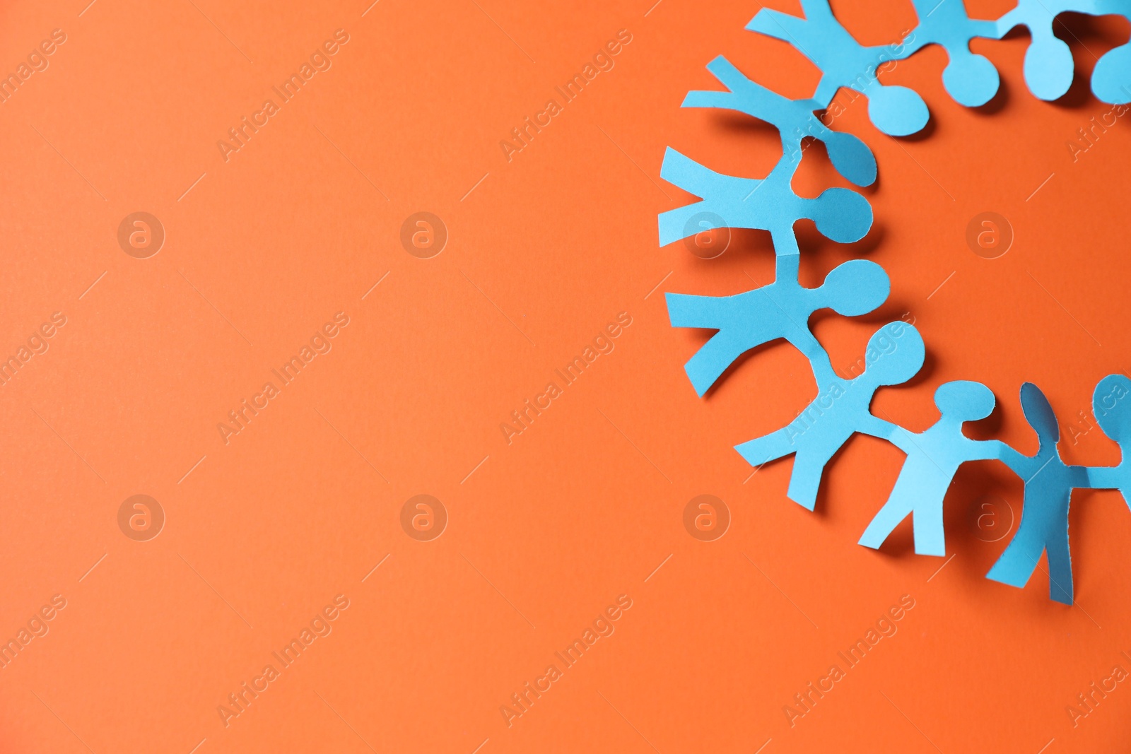 Paper figures of people holding hands on orange background, top view. Space for text Photo of Paper figures of people holding hands on orange background, top view. Space for text
