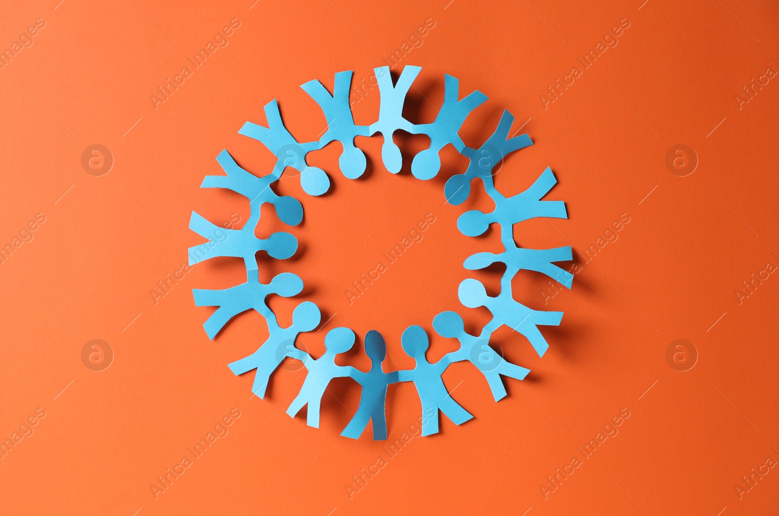 Paper figures of people holding hands on orange background, top view Photo of Paper figures of people holding hands on orange background, top view