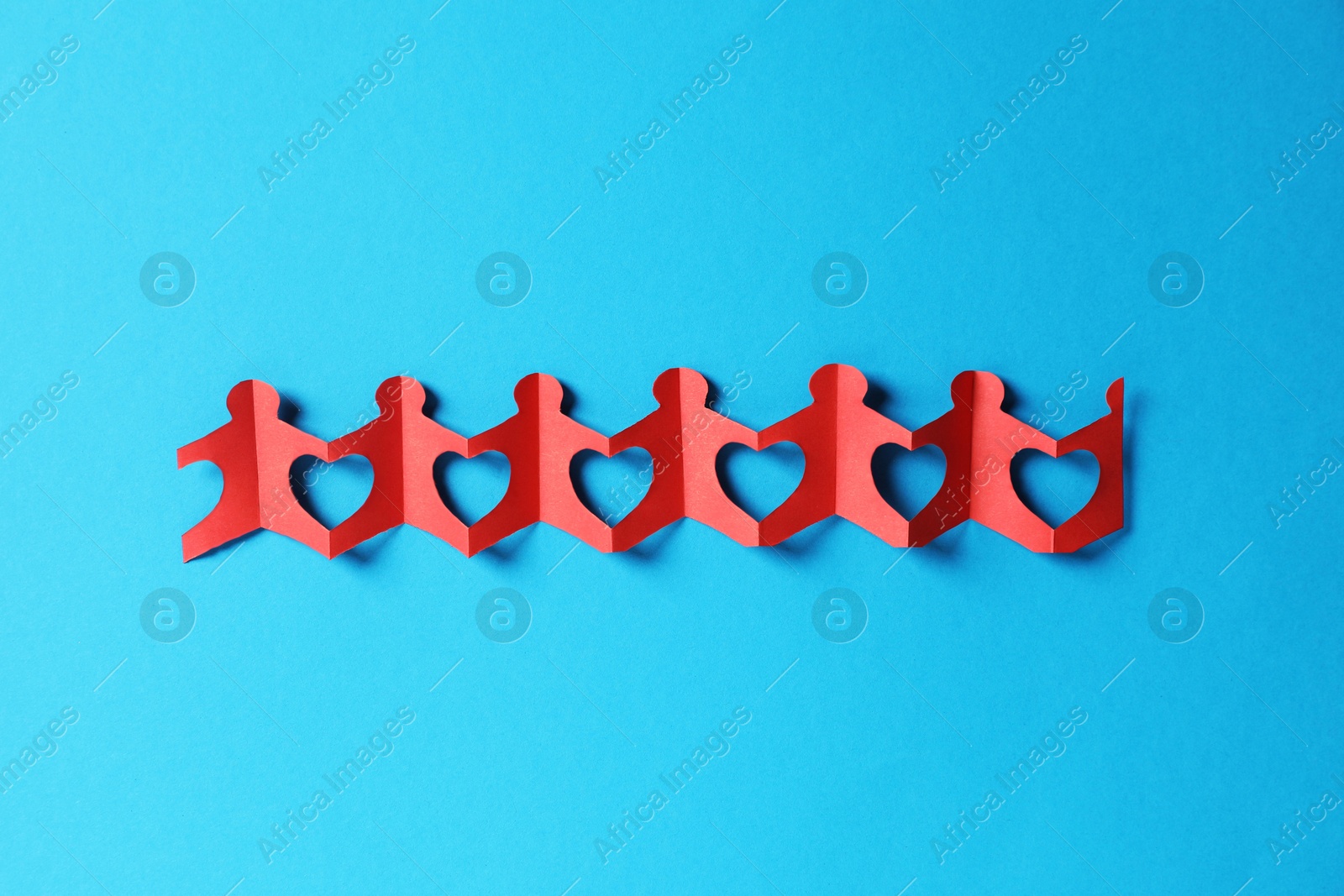 Paper figures of people holding hands on light blue background, top view Photo of Paper figures of people holding hands on light blue background, top view