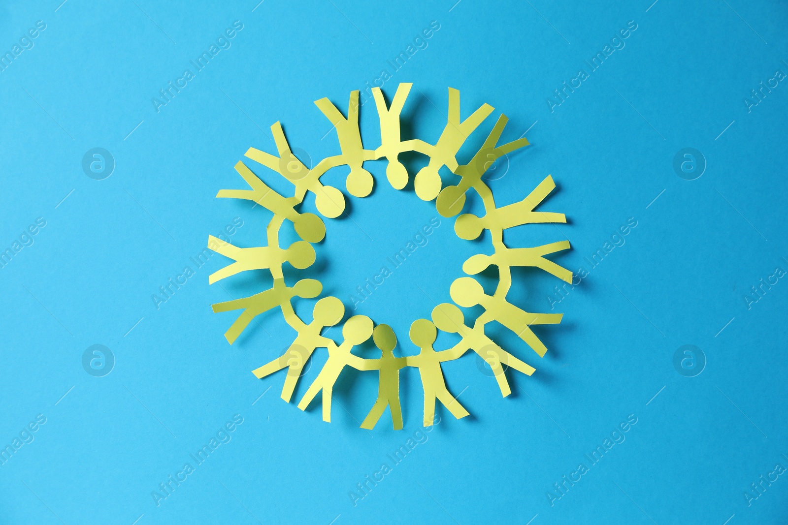 Paper figures of people holding hands on light blue background, top view Photo of Paper figures of people holding hands on light blue background, top view