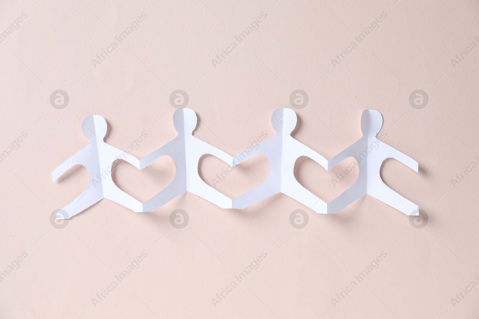 Paper figures of people holding hands on beige background, top view Photo of Paper figures of people holding hands on beige background, top view