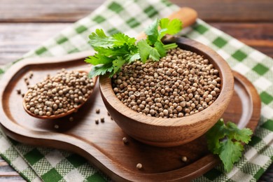 Photo of Coriander seeds and fresh cilantro sprigs on wooden table, closeup