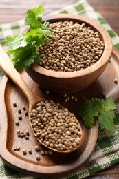 Photo of Coriander seeds and fresh cilantro sprigs on wooden table, closeup