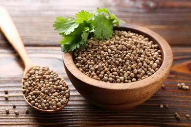Photo of Coriander seeds and fresh cilantro leaves on wooden table, closeup