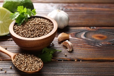 Photo of Coriander seeds, fresh cilantro, lime and garlic on wooden table, closeup. Space for text
