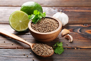 Photo of Coriander seeds, fresh cilantro, lime and garlic on wooden table, closeup